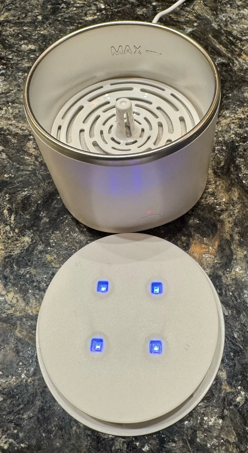 An ultrasonic cleaner with clear aligner attachments arranged beside it.