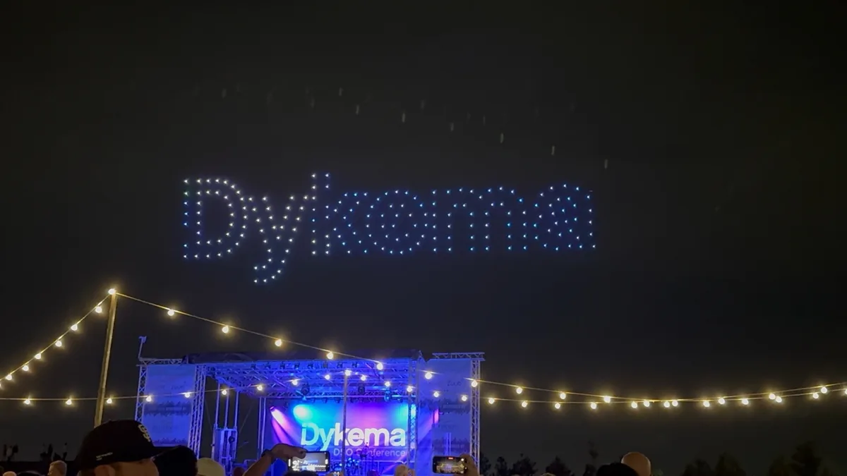 A drone light show spelling out Dykema above the conference stage.