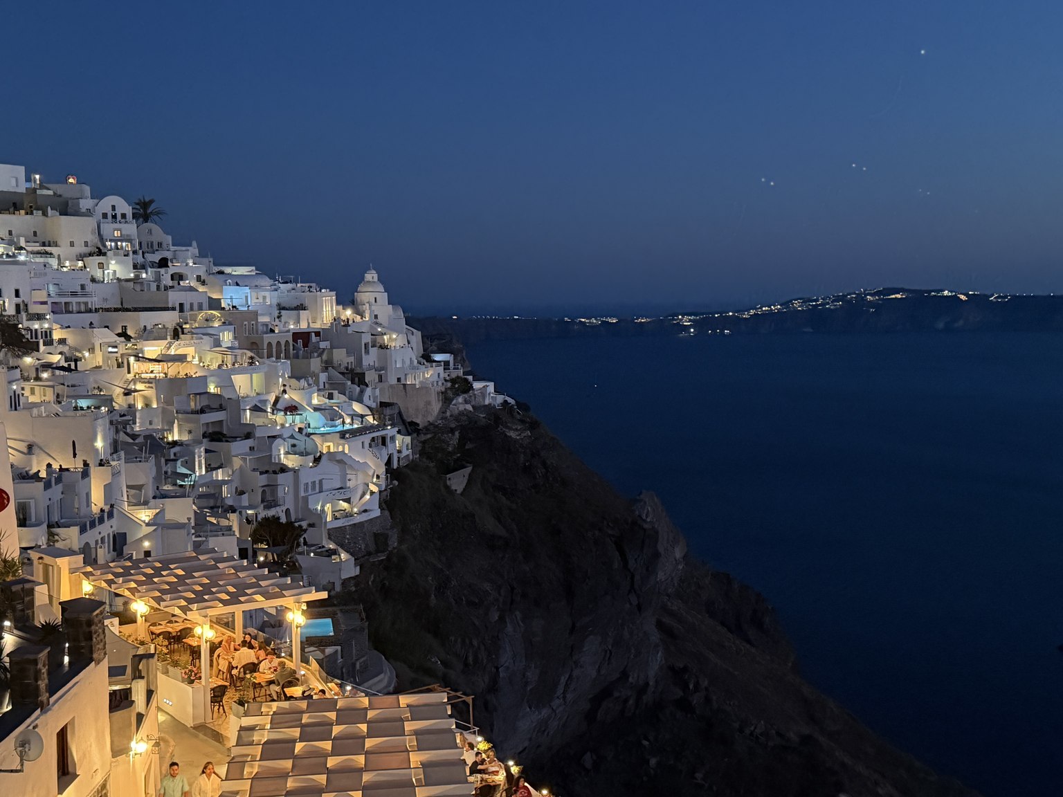 Santorini's caldera lit up at night, site of the next Luxury Dental Retreat