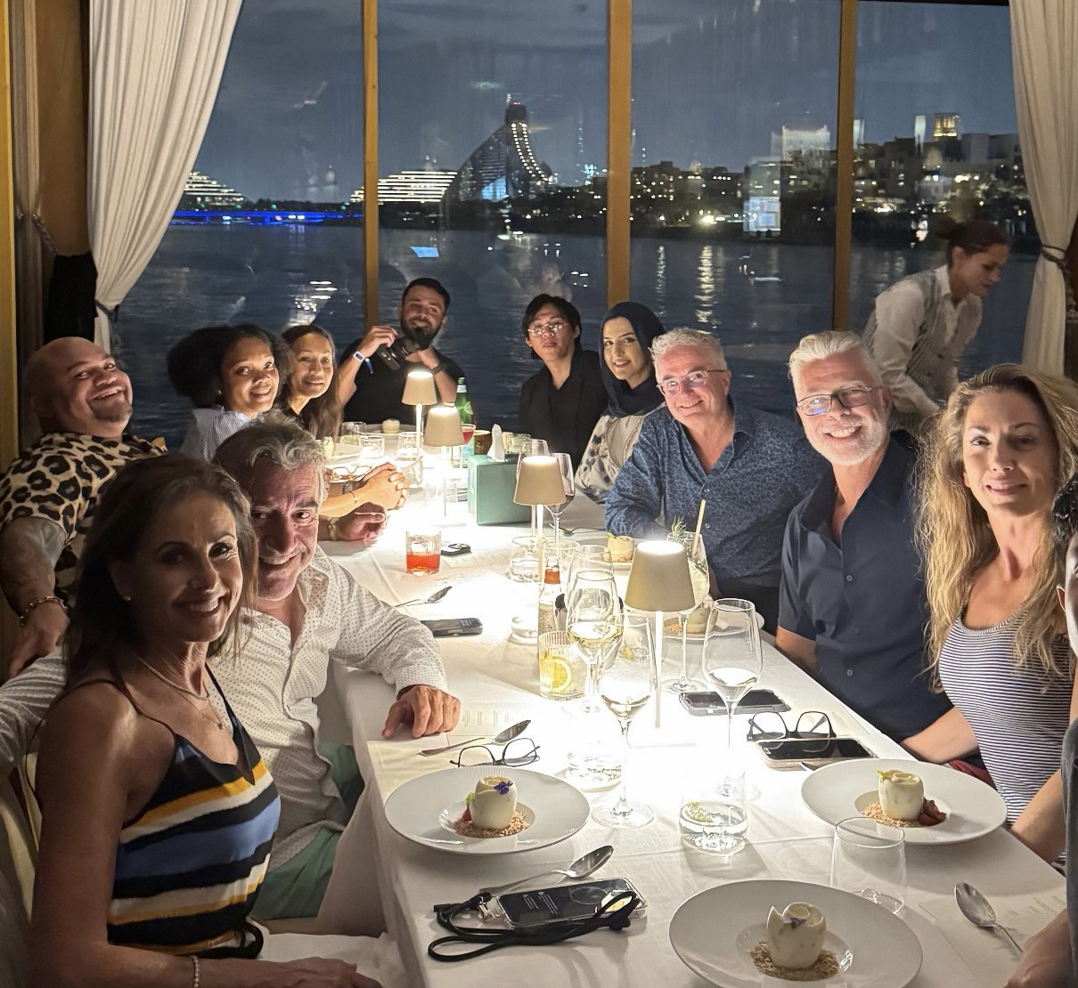 The retreat group at a waterfront dinner with the Dubai skyline lit up across the water