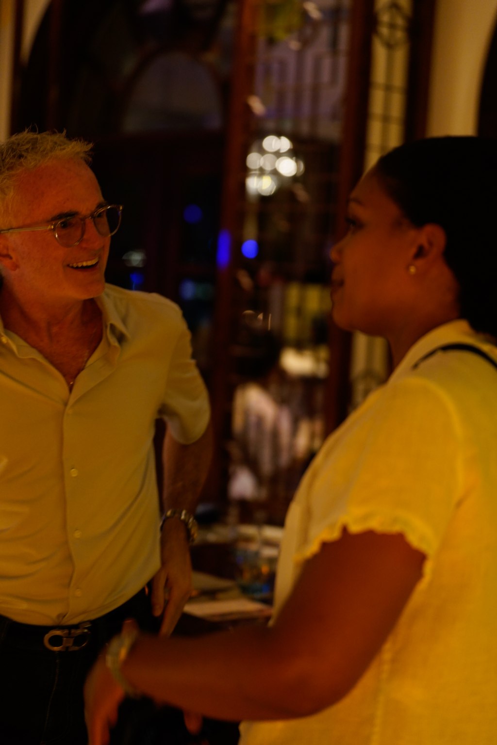 Two retreat attendees in conversation at a candlelit restaurant
