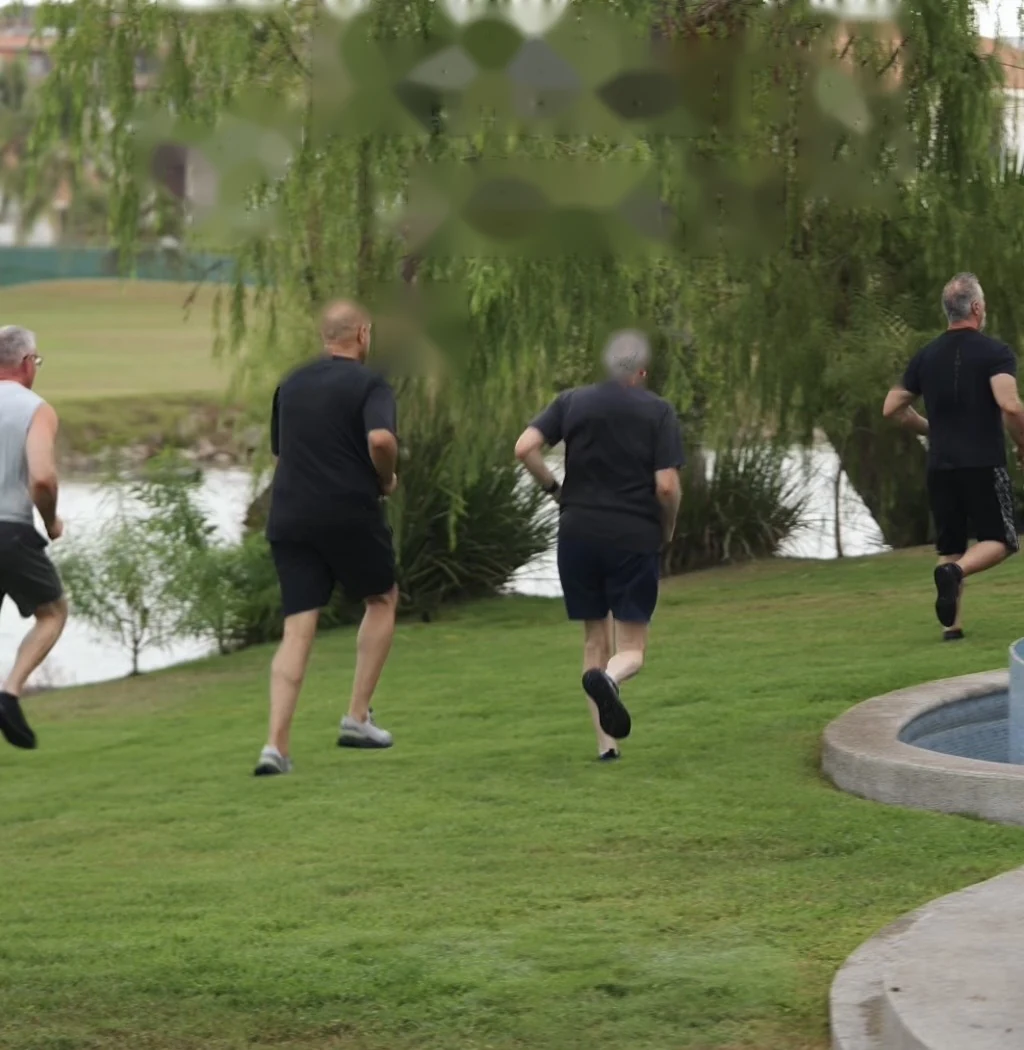 The group running across the lawn past the fountain