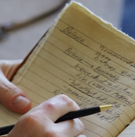 A hand writing in an open leather journal