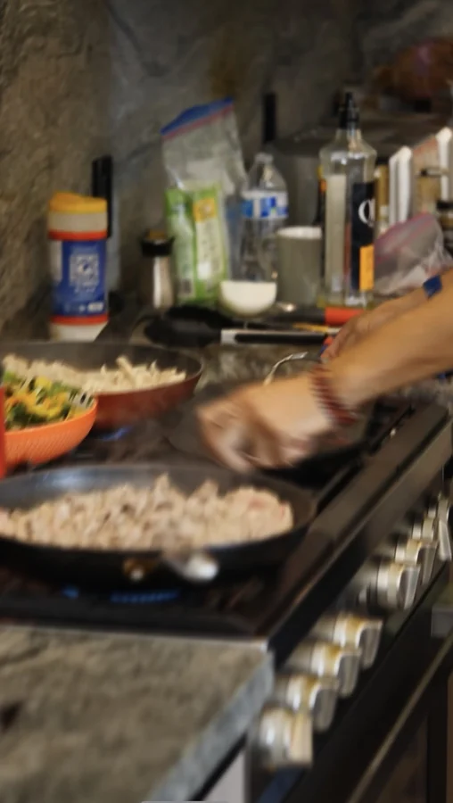 A chef working at the stove with pans on the burners