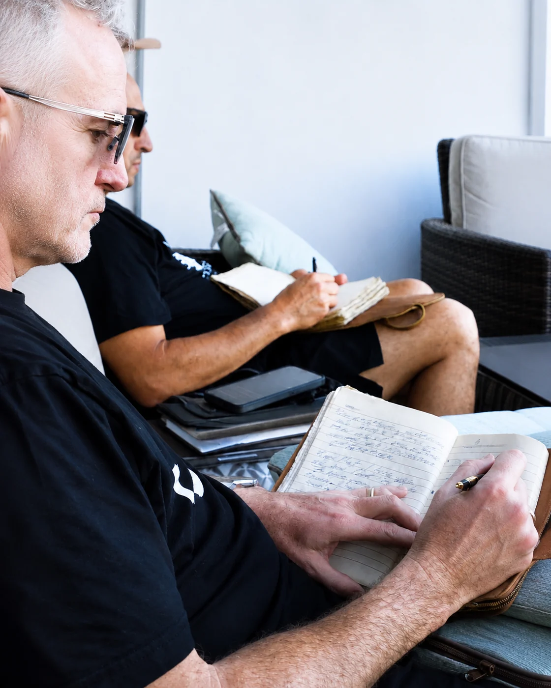 Two dentists writing in leather journals on the terrace